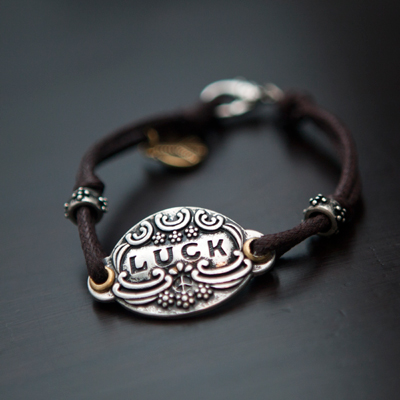 LUCKY BRAND® Basics Leather Bracelet - 7" slender, leather band bracelet featuring silver-toned "Luck" pendant surrounded by two silver-tone raised floral rings and gold-toned "Peace" mini-charm.